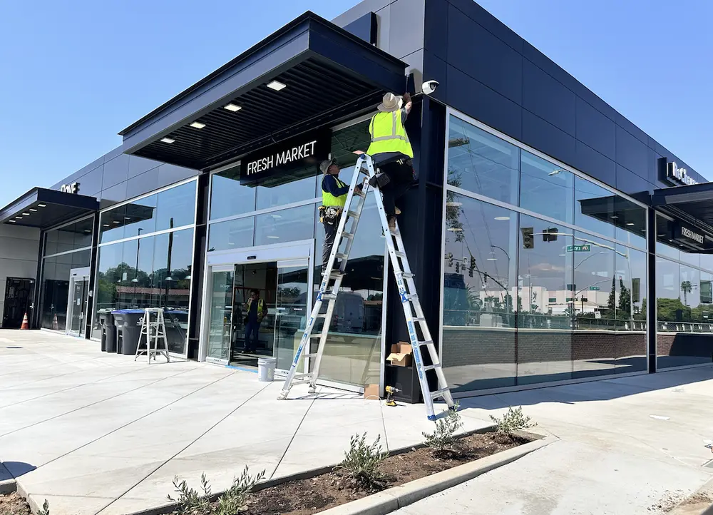 Security technicians installing an exterior camera at a modern fresh-market property